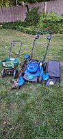Overall shot showing mower, trimmer, spreader, grass bag, battery and charger