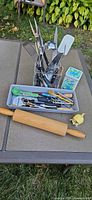 All loose kitchen utensils laid out including rolling pin, citrus juicer, utensil holder with serving tools, cutlery and accessories