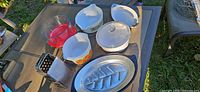Overall shot showing fish platter, Pyrex bowls and casseroles, and two box graters on patio table