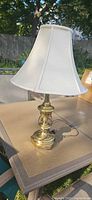Full view of brass table lamp with white shade on table