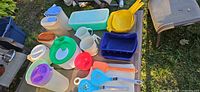 Assorted Tupperware containers, silicone bake pan, colander and spatulas on outdoor table
