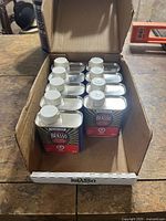 Open cardboard sleeve showing nine unopened Brasso 142 ml metal polish cans