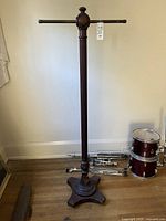 Full view of tall wooden garment rack on four-footed base