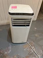 Front view of white portable dehumidifier showing louvers and power cord