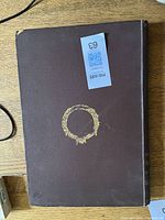 Front cover of brown cloth hardcover book with gilt circle emblem
