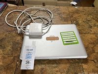 Closed MacBook Pro top view with Apple logo, green asset sticker, bundled MagSafe charger
