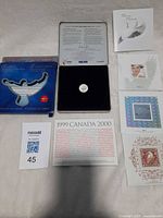 Full lot view showing coin in tin, sleeve, and literature