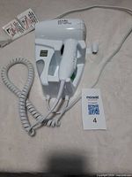 Full view of Andis wall-mount hair dryer with handset in cradle and coiled cord visible