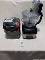 Full view of food processor assembled beside blade storage case