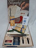 Full view of Sheaffer calligraphy set box with tray, ink cartridges, pen barrel, nib sections, and packaged Speedball items
