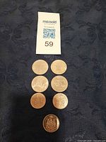 Full view of all seven coins laid out on dark fabric