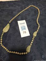 Full view of necklace showing beaded strand and three leaf pendants