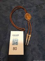 Full view of bolo tie showing braided cord, stone slide, metal tips