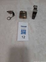 Entire lot: revolver keychain, ornate lighter, Acme whistle next to lot card