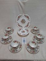 Full set arranged showing cake plate at back, five dessert plates, six cups with saucers