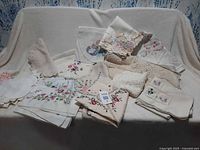 Overview of assorted embroidered and crocheted table linens on sofa