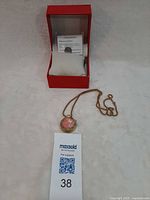 Pendant watch, chain, presentation box, spare battery visible