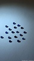 Group of 18 blue sapphires on white background under spotlight