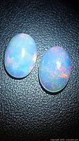 Both opal cabochons showing color play on black background