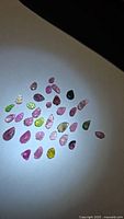 Group of multicoloured leaf-cut tourmalines under spotlight