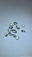 Group of 12 faceted yellow-green tanzanite stones on white background
