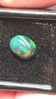 Opal showing green and yellow flashes on dark body