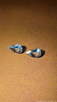 Pair of pear-cut aquamarines on brown surface