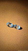 Pair of oval cut aquamarines on brown surface