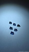 Six square blue sapphires arranged point up on neutral background