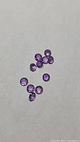 Ten round purple amethysts on neutral background