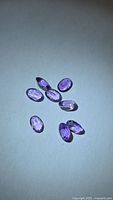 Seven oval purple amethysts on light background