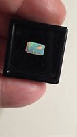 Emerald-cut Ethiopian opal in display box showing play-of-colour