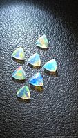 Seven faceted trillion opals on dark background