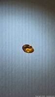 Oval faceted orange-yellow sapphire on neutral background