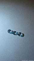 Three pear-cut blue zircons on neutral background