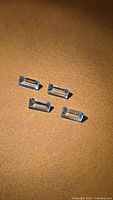 Four rectangular light blue gemstones on brown surface