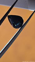 Pear cut deep blue spinel held by tweezers
