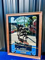 Full view of framed Captain Norton advertising mirror against metal wall