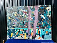 Full view of abstract oil painting on blue cloth backdrop