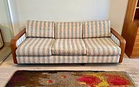 Front view of three-seat teak frame sofa with striped upholstery