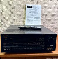 Front view of Pioneer VSX-D701S receiver with remote on top and manual behind