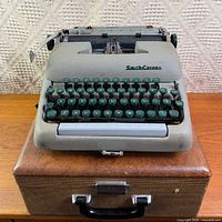 Typewriter sitting on closed carry case, full view