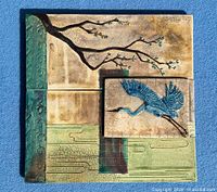 Full frontal view showing entire square tile, layered panels, crane relief, glaze colors