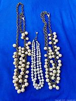 Three necklaces laid out on blue cloth