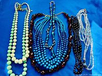 All six necklaces laid out on blue background