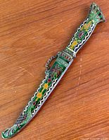 Full view of brass cloisonné letter opener in sheath on wooden surface