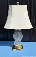 Full view of lamp showing crystal body, brass base, shade, finial