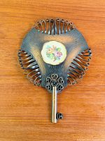 Front view of metal plaque with floral embroidery