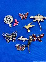 Group shot showing all ten brooches on blue background