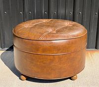Overall view of round brown tufted foot stool with casters